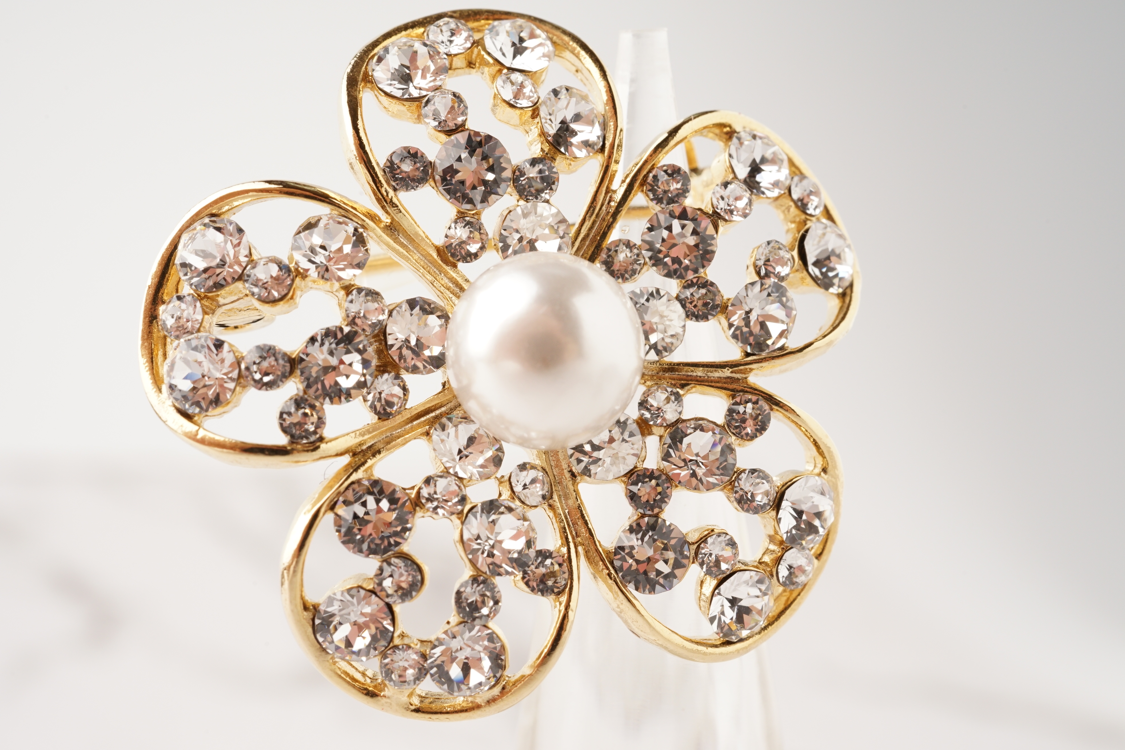 大きな真珠が中央にあり、花びらを模した台座に石が埋め込まれた華やかなブローチ